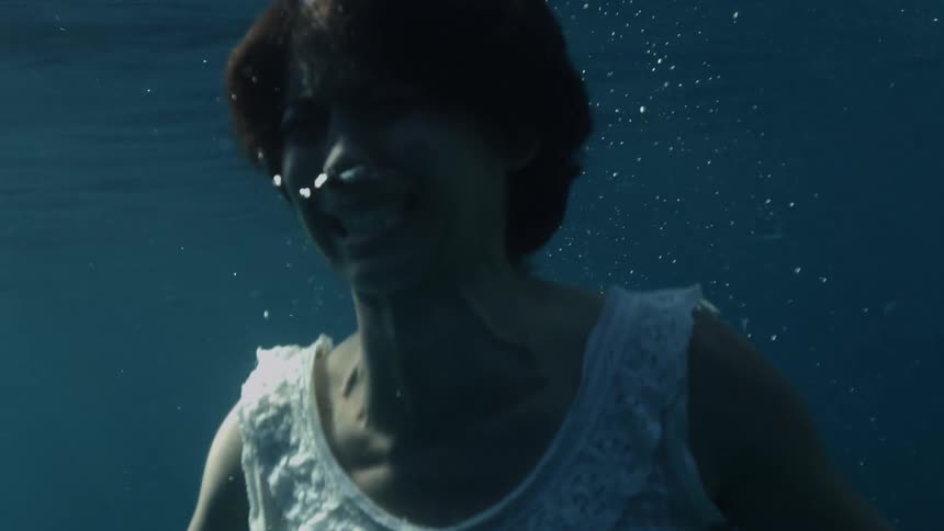An upset woman in a thin nightgown struggles to paddle to the waters surface