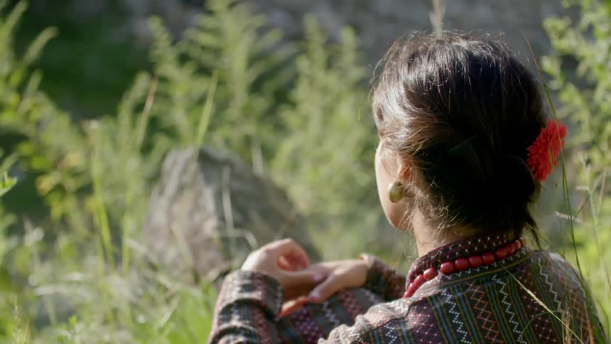 A woman is sitting down in the grass on a sunny day