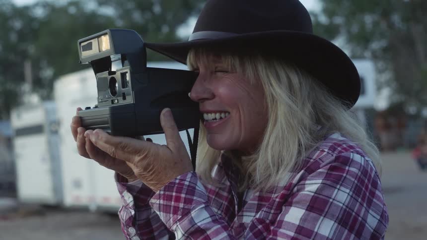 A middle aged woman takes a photograph with an instant camera