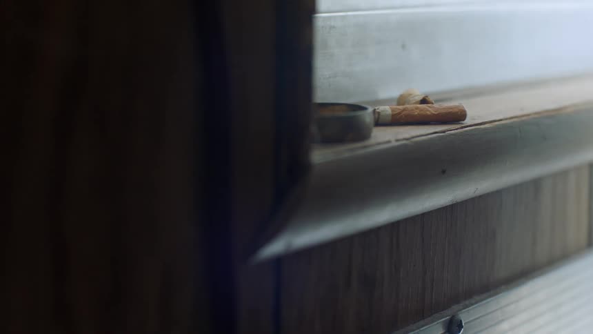 A cigarette lying next to an ashtray on a window sill
