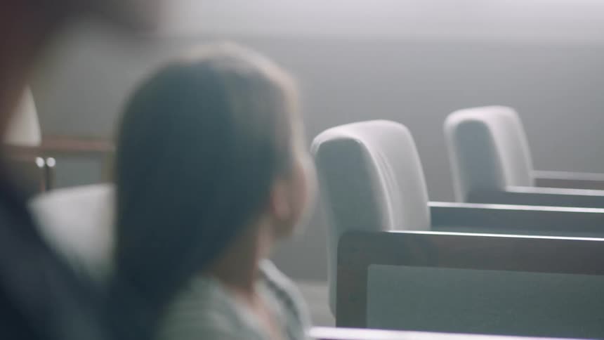 A little girl sits in a chair and glances over to a row of empty chairs to her left