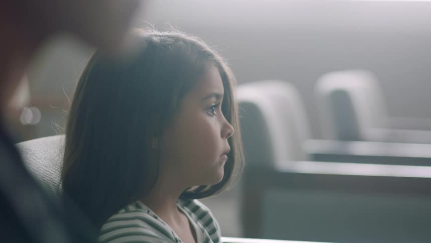 A young girl sits next to an older woman in a courtroom