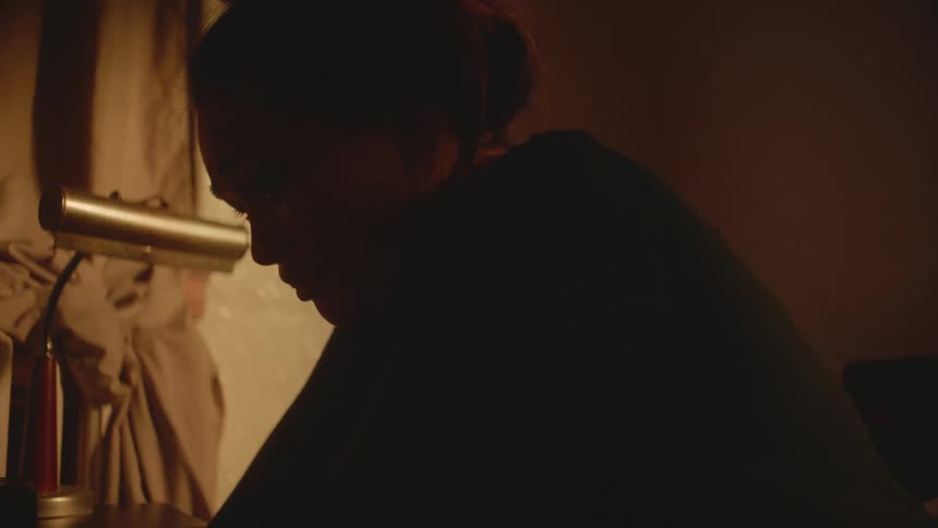 Fearful woman sitting in a dimly lit room suddenly stands up
