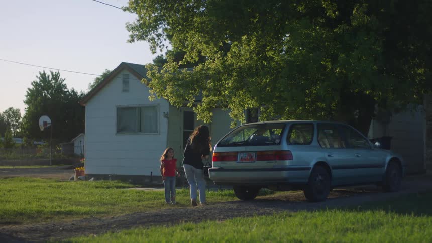 Mother opens a car trunk and throws a bag inside and then rushes her daughter into the backseat