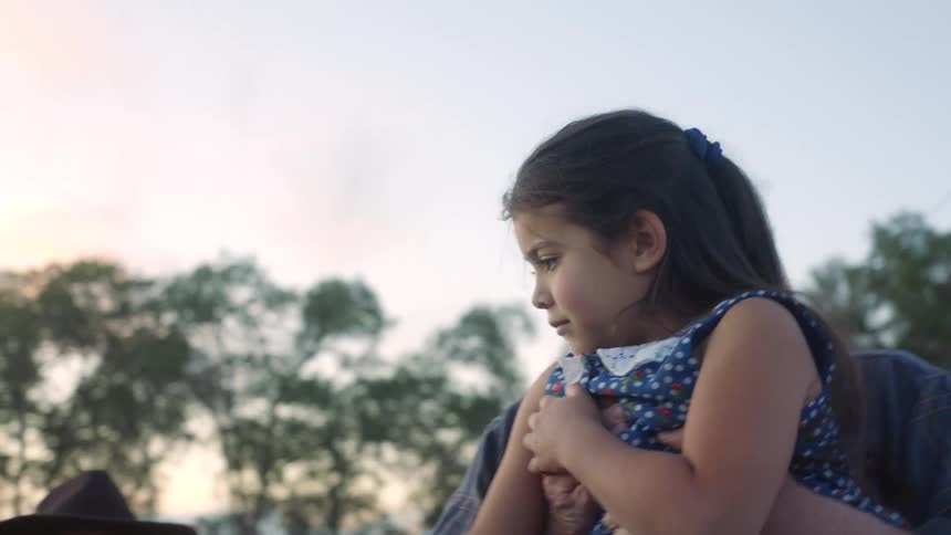 Little girl hiding behind her grandfather scared to pet a horse as he lifts her up and she puts her hand on the horses nose