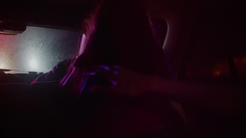A little girl sits up and looks out the window of a car at the approaching policeman