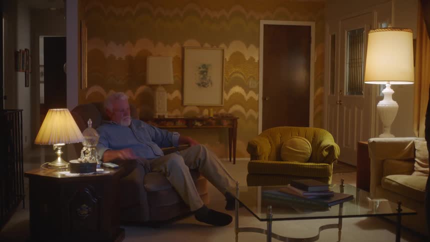 Man sitting in a recliner in a living room gets up to check the door