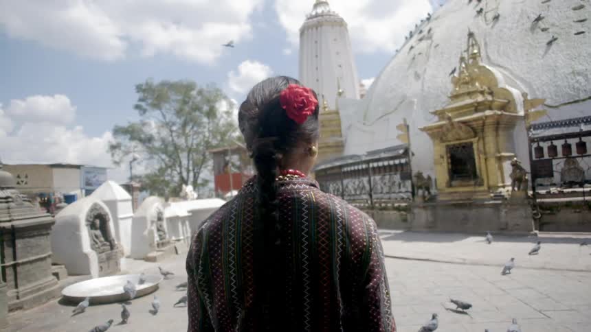 A woman stands in a courtyard looking at a temple