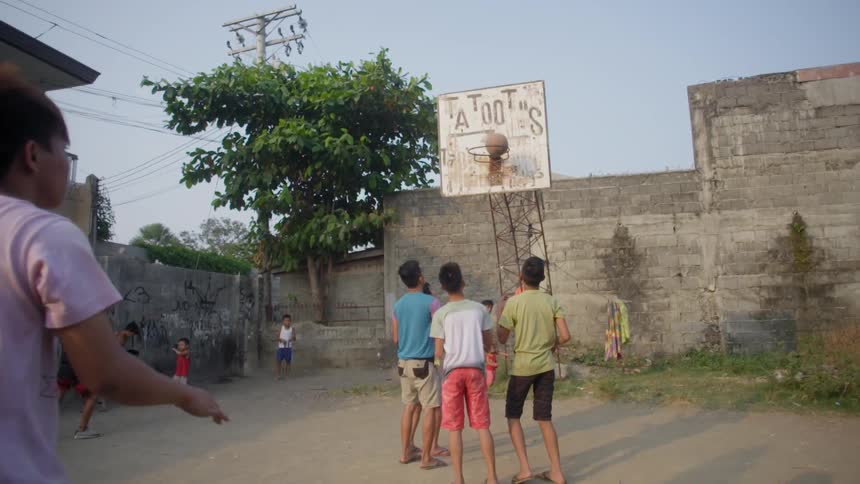Boy making a long basketball shot on a rundown playground