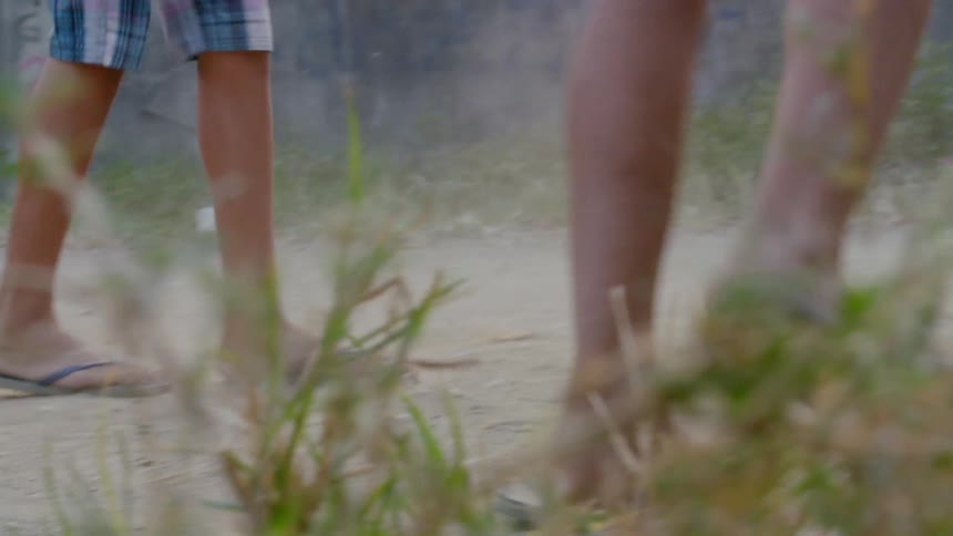 Boys play a game of basketball in flip flops on a dirt court