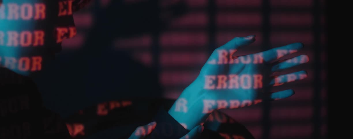 Red text letters projected over the hands and face of a young woman in a dark room