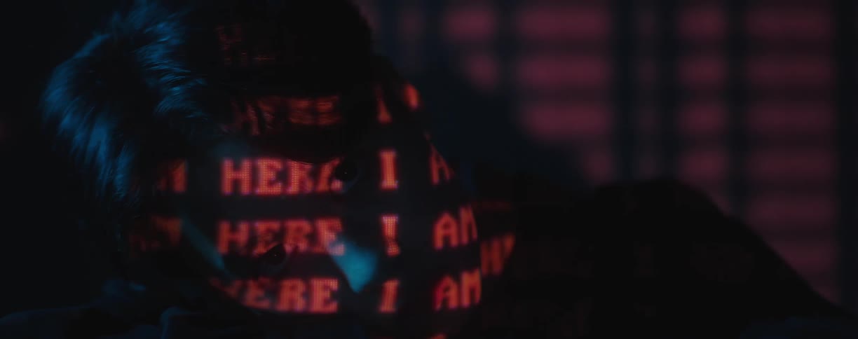 An asian teen with his head on his arms and the words i am here projecting on his face