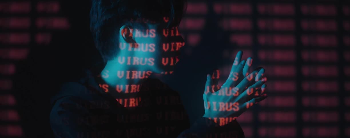 Red text projected over the face and hands of a young woman in a dark room