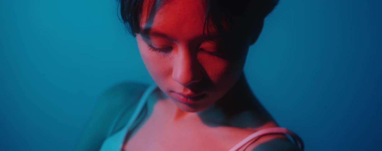 A red light shines on a models face as she poses indoors