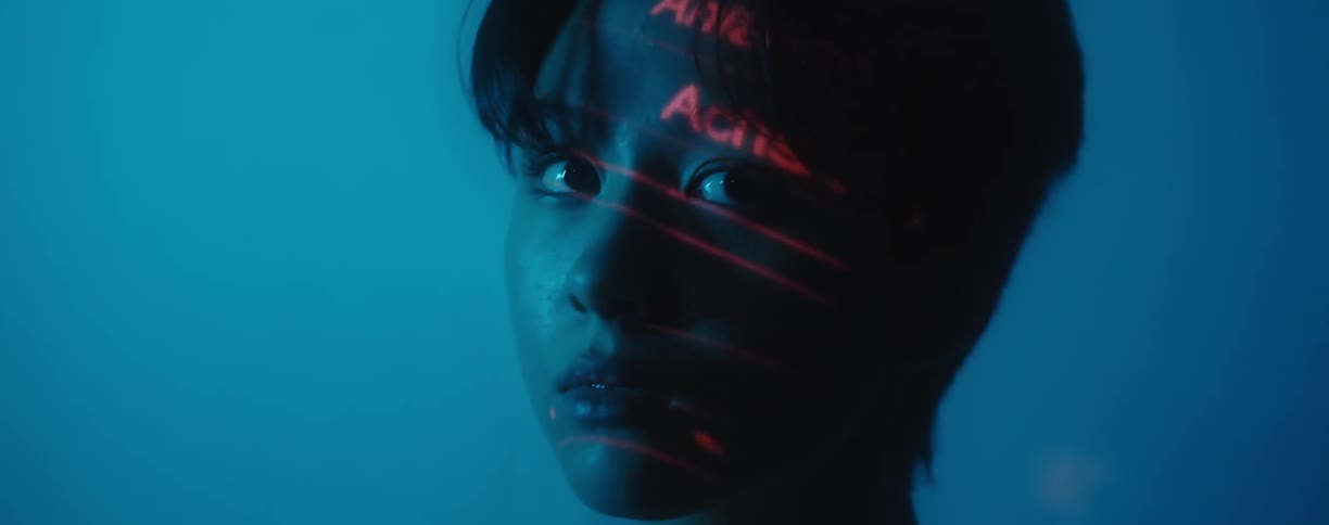 A teenage girl with lights flashing on her face looks around a room