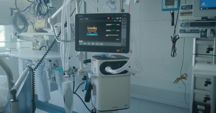 Medical monitor displaying a standby screen in a room filled with medical equipment