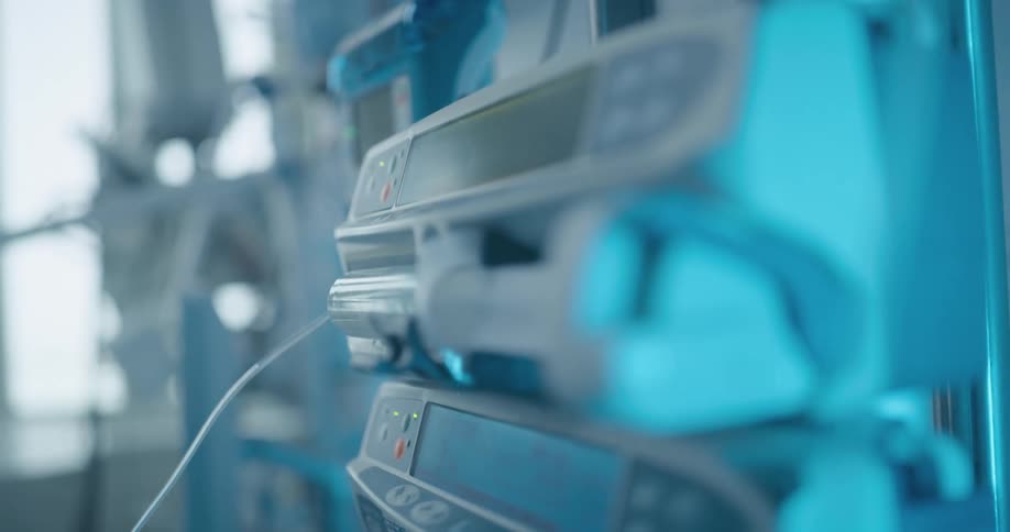 A person presses a button on a syringe pump that is connected to multiple plastic syringes