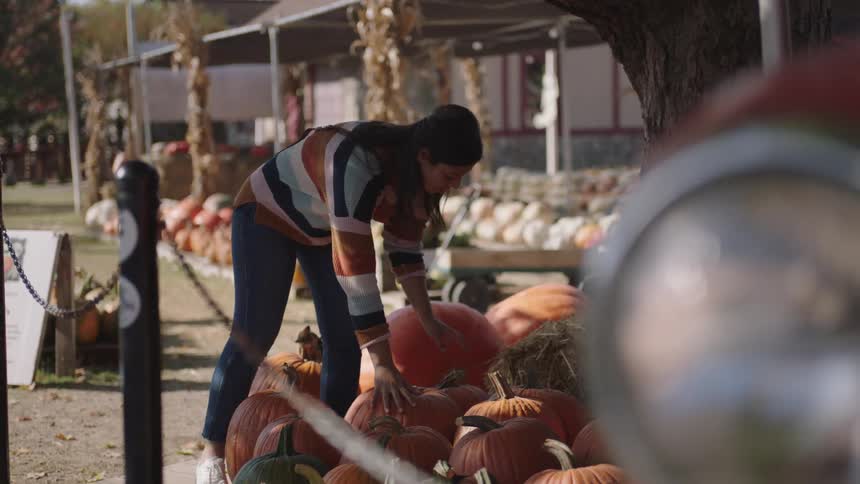 A woman comparing pumpkins