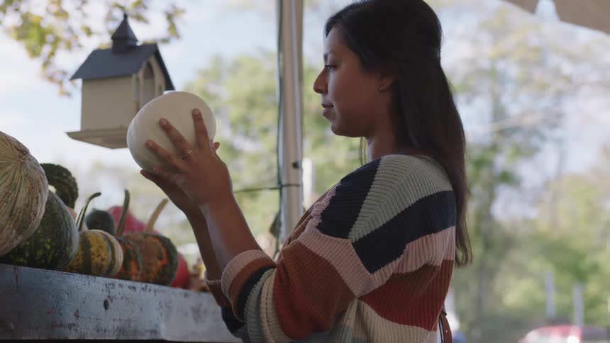 Woman buying pumpkins in a stall on a street market
