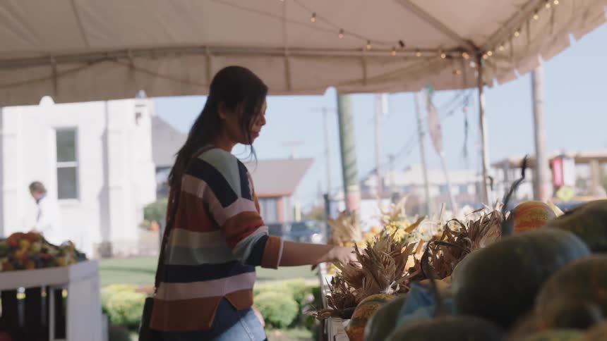 A teenager looks at pumpkins at a market