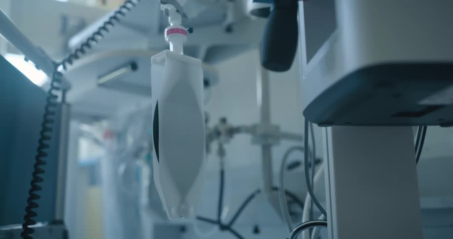 White medical equipment with black cords andwires behind a bed