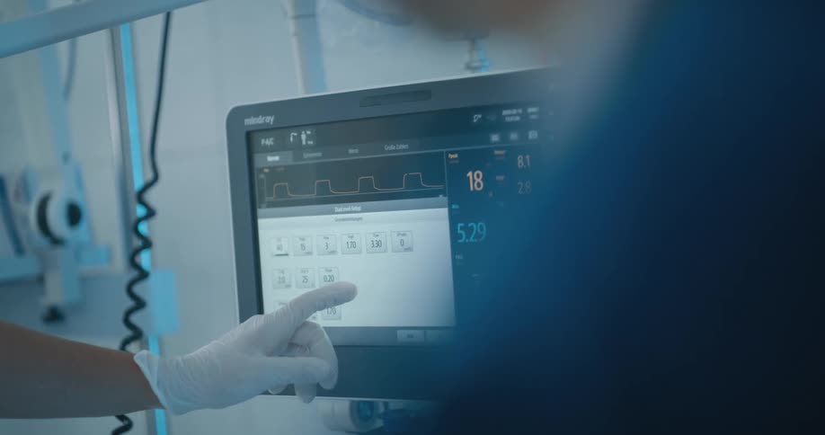 A person wearing a disposable glove uses a touchscreen to control a medical device