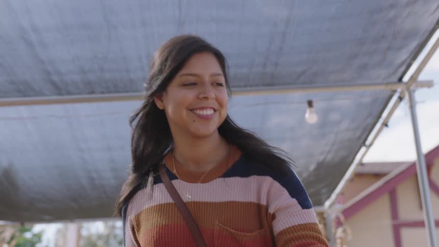 A woman is outdoors shopping for pumpkins