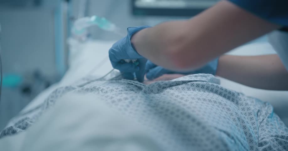 Two nurses attach medical sensors to a patient as he lies in a hospital bed