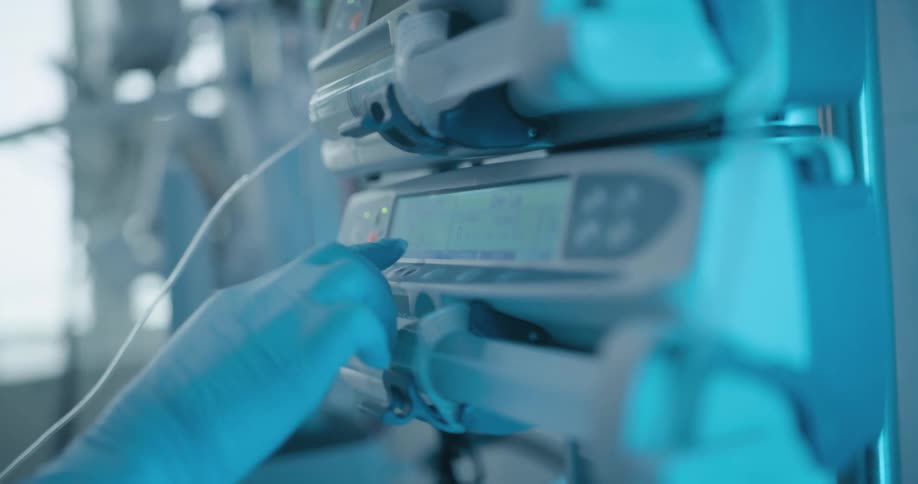 A nurse in a hospital presses buttons on medical equipment