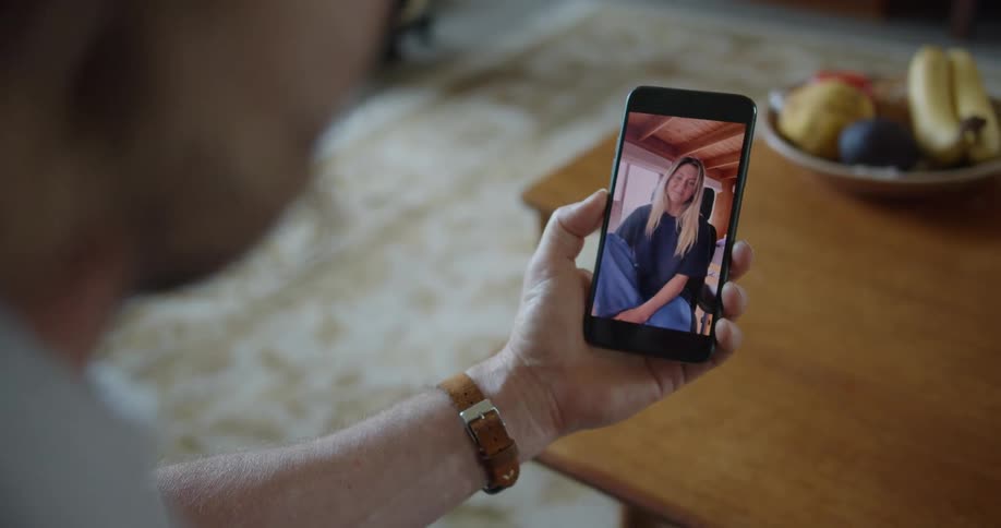 A person in a room with a wristwatch video chatting on a smart phone