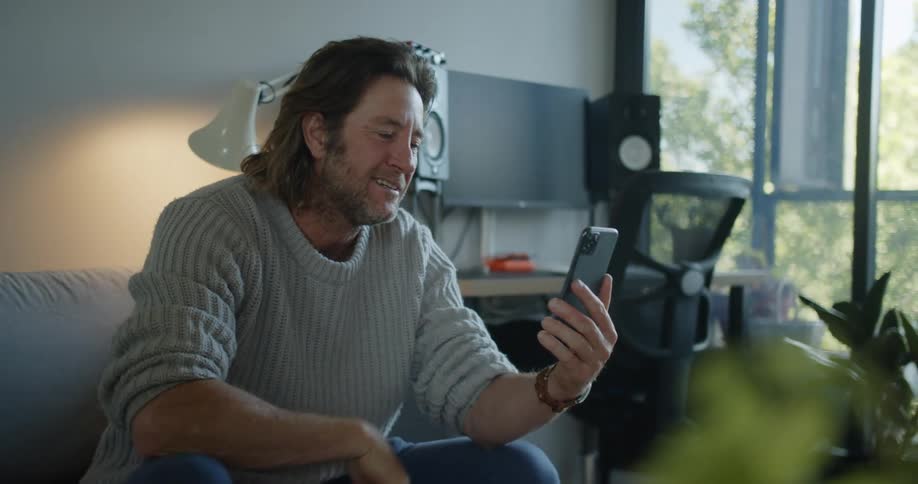 Man sitting in a couch at home says goodbye in a video call over the phone