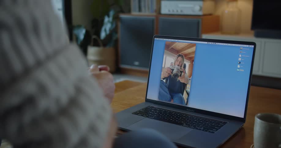 Person watches woman show off her camera via video call on laptop