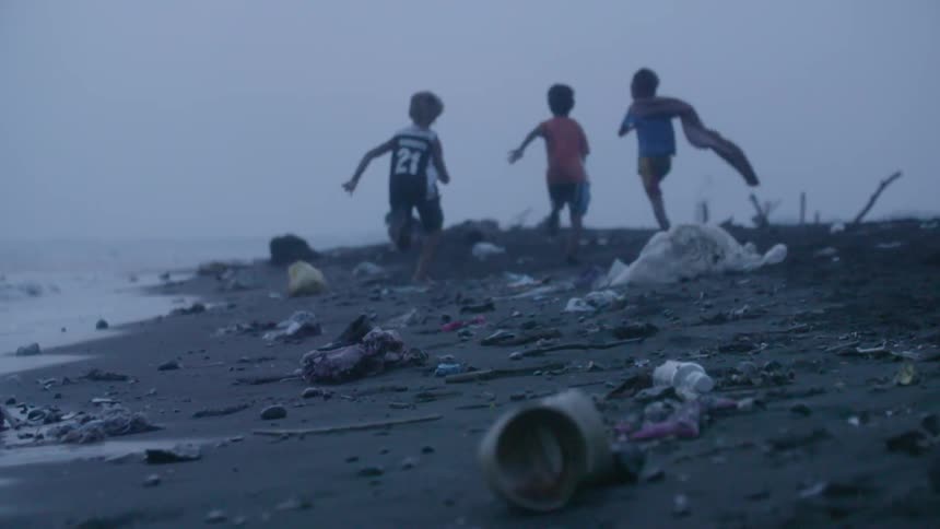 Children running along a debris-strewn shoreline