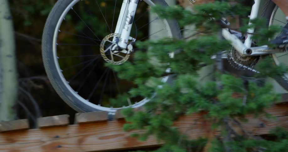 A biker on a trail with a small wooden bridge