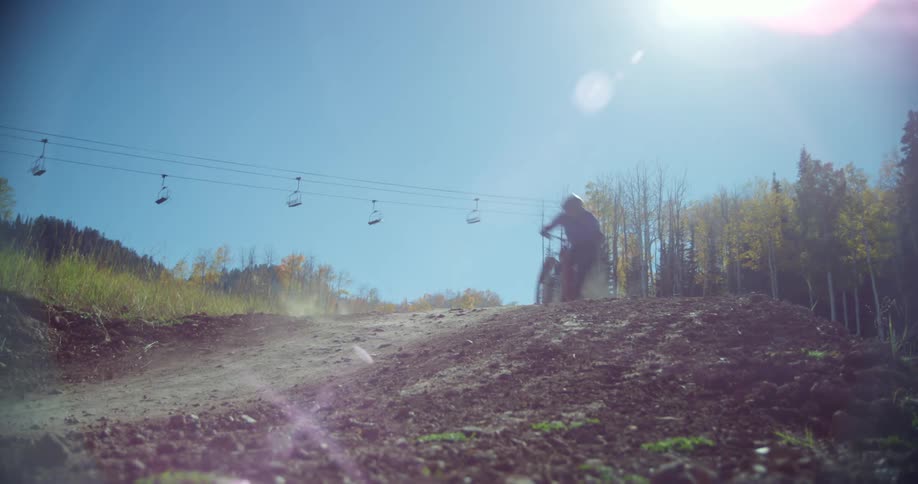 Two cyclists riding mountain bikes on a dirt road near the forest on a clear sunny day