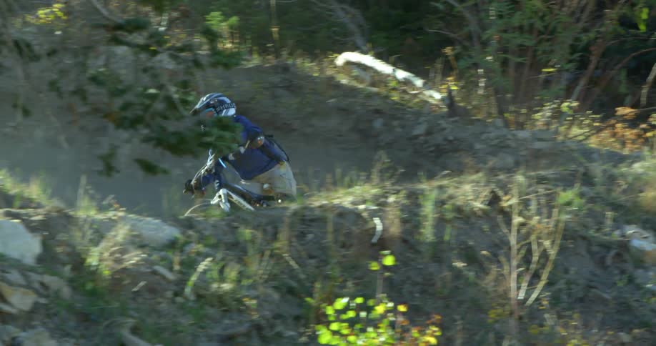 A person with a helmet and a backpack riding a bike on a dirt course in the woods