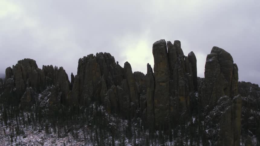 Light snow falls over a mountain and collects in the rugged terrain