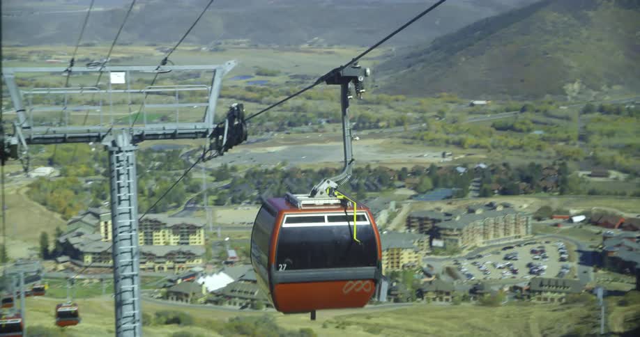 A gondola lift moves quickly down cable lines that head to a resort