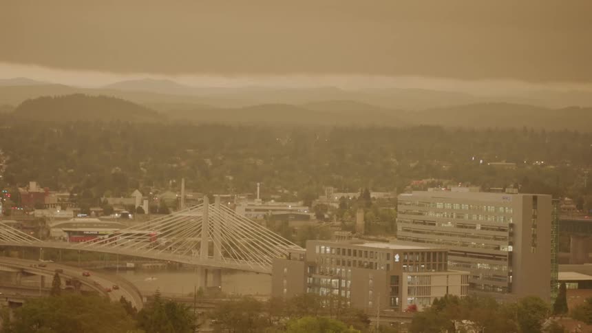 View of a city with cars driving on highways next to buildings and a river