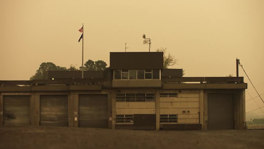 Abandoned building with broken garage doors under a yellow sky