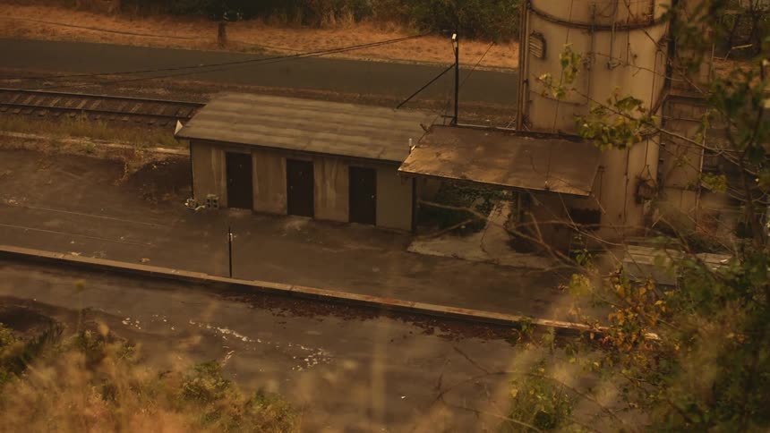 Old building next to a train track in a rural forested area