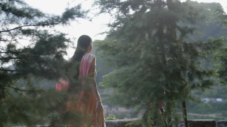 A woman and child walk behind some trees