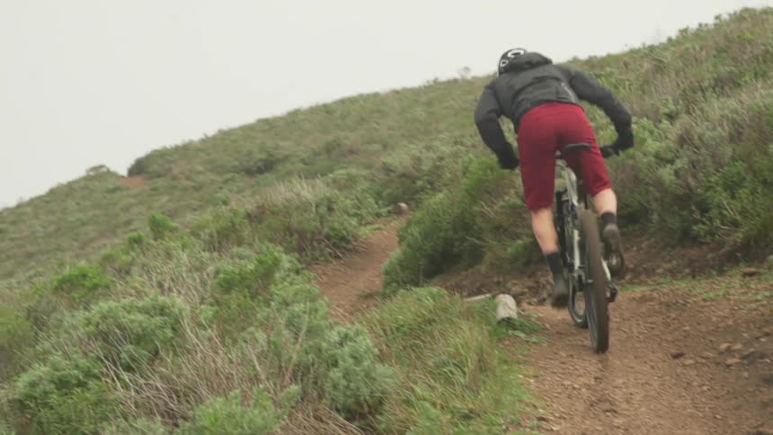 Male cyclist cycles uphill on a dirt road on