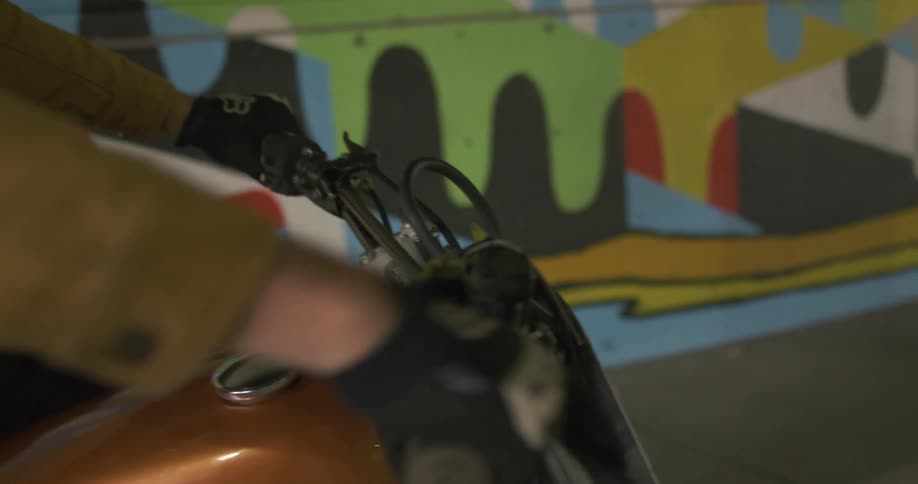 A man starts up his motorbike and rides through a parking garage