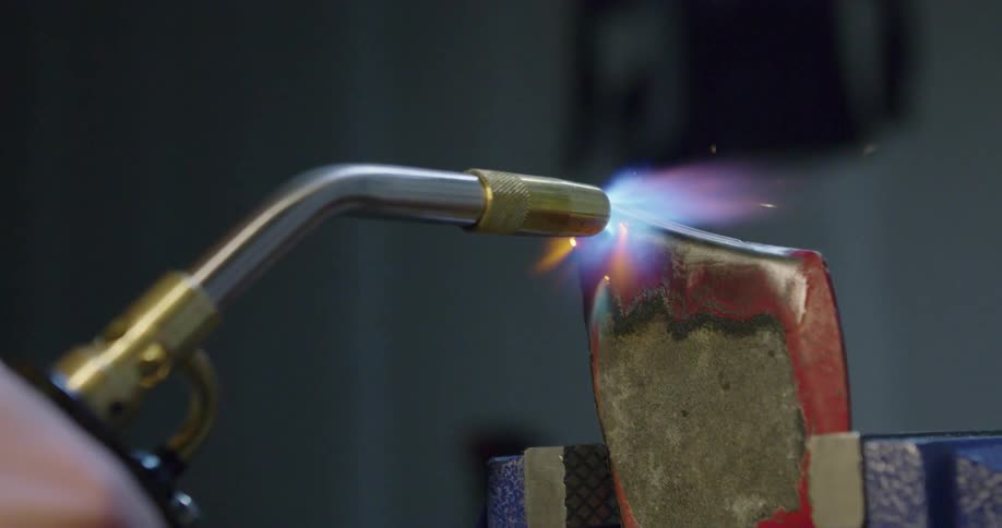 A person uses a torch to heat up metal
