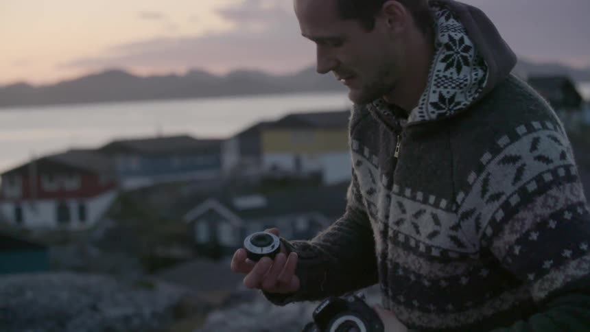 A man examines a camera lens in his hand