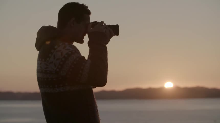 A man is taking photographs at sunset