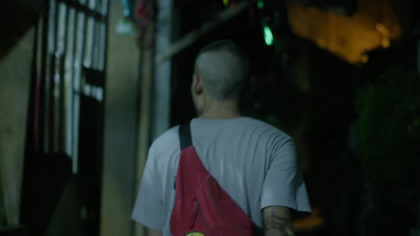 A man is walking down an alley at night
