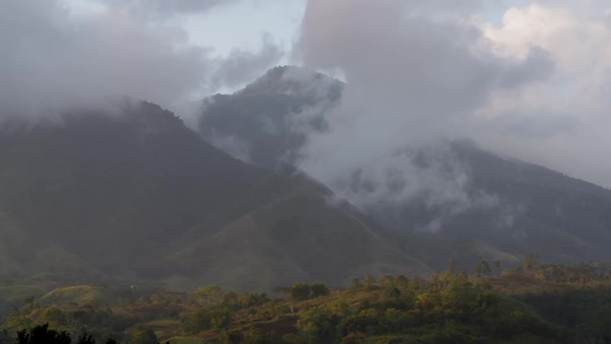 Low clouds flowing by a large mountain
