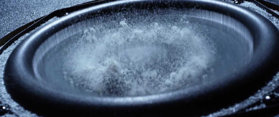 White powder is moving on a black speaker head due to noise vibration